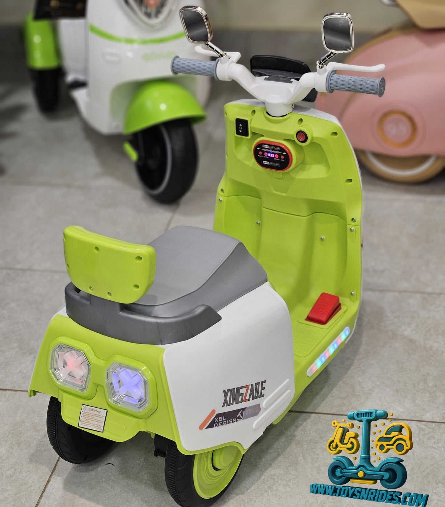 Green and white toy scooter with a seat on a tiled floor, brand 'Toyshrides' visible.