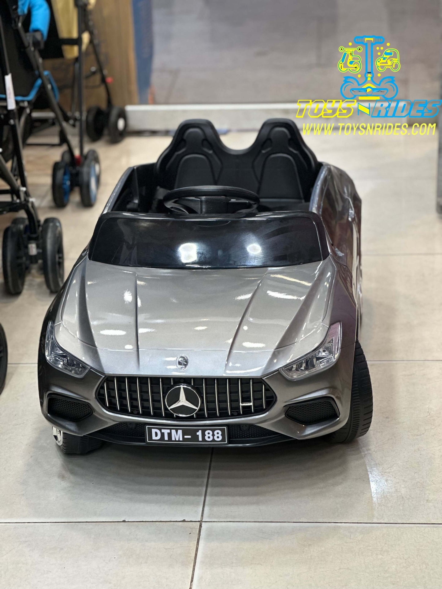 Happy toddler driving TOYSNRIDES Mercedes electric car outdoors