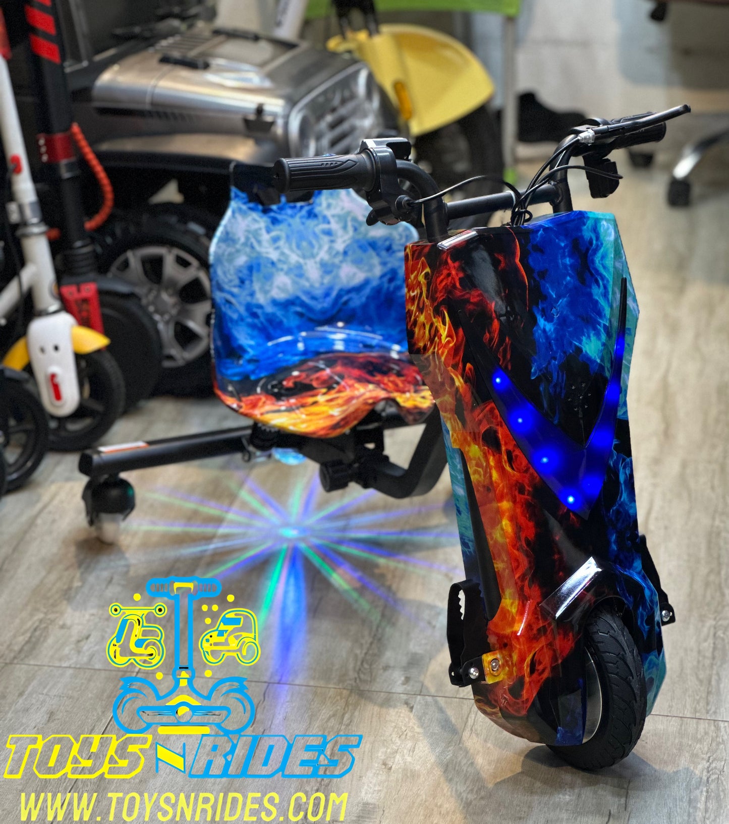 Colorful electric Drifting scooter with flame design on a wooden floor, brand 'TOYS N RIDES' visible.