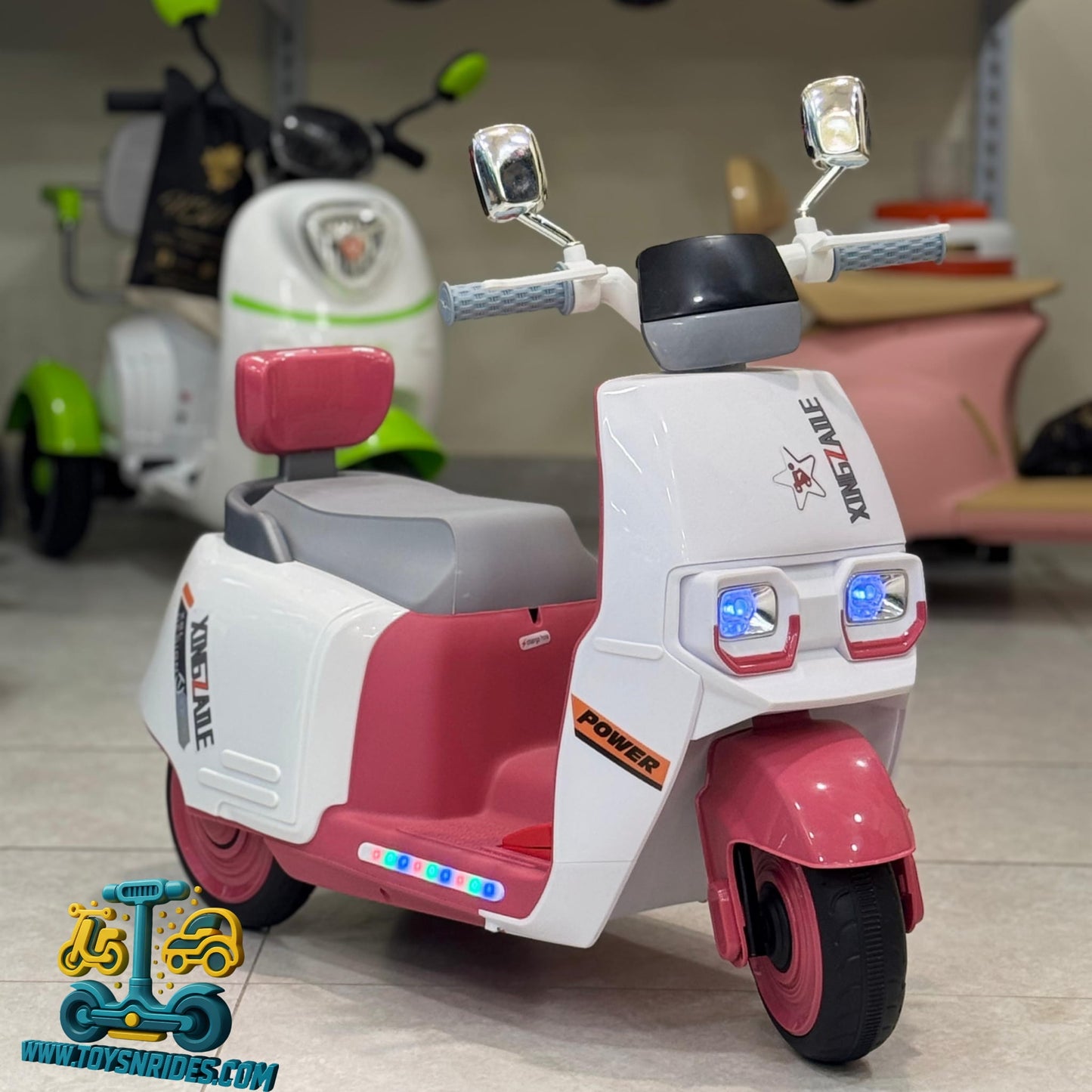 Pink and white toy scooter with visible branding in a room setting