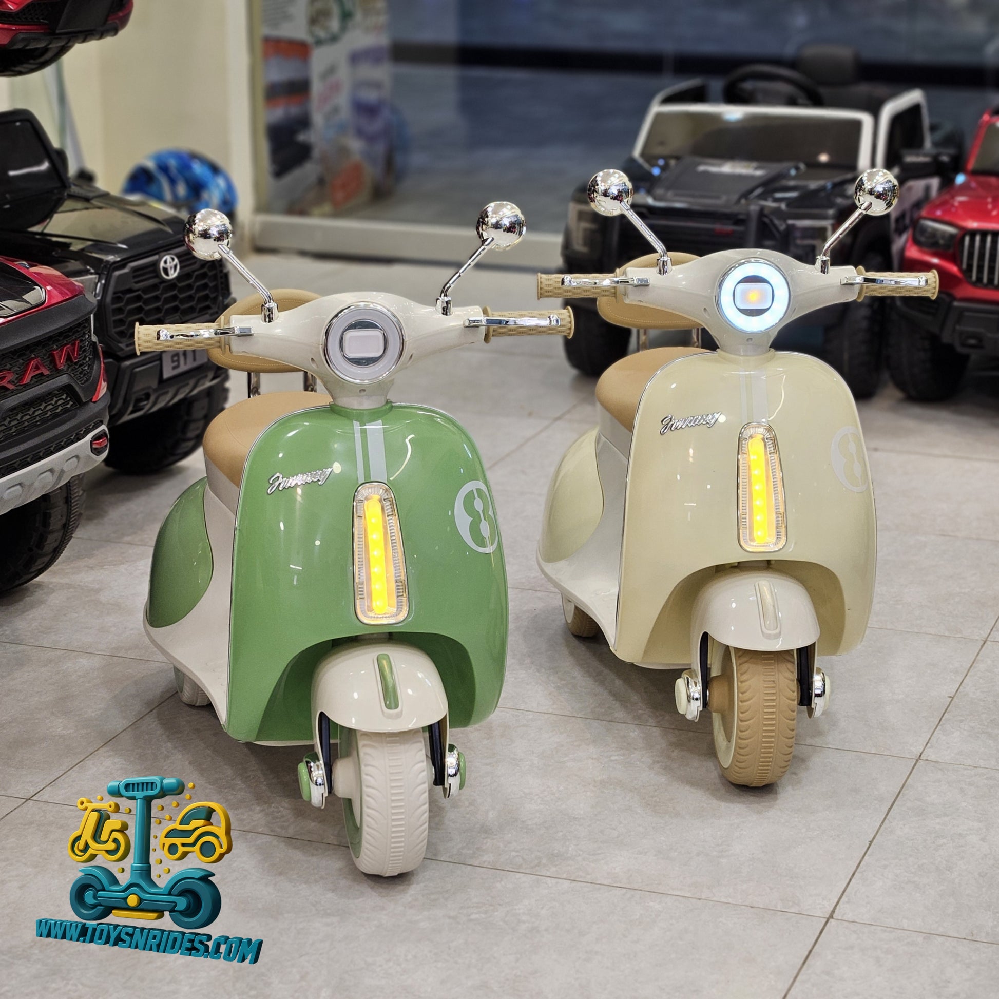 Two toy scooters, one green and one beige, in a showroom setting with other toys in the background.