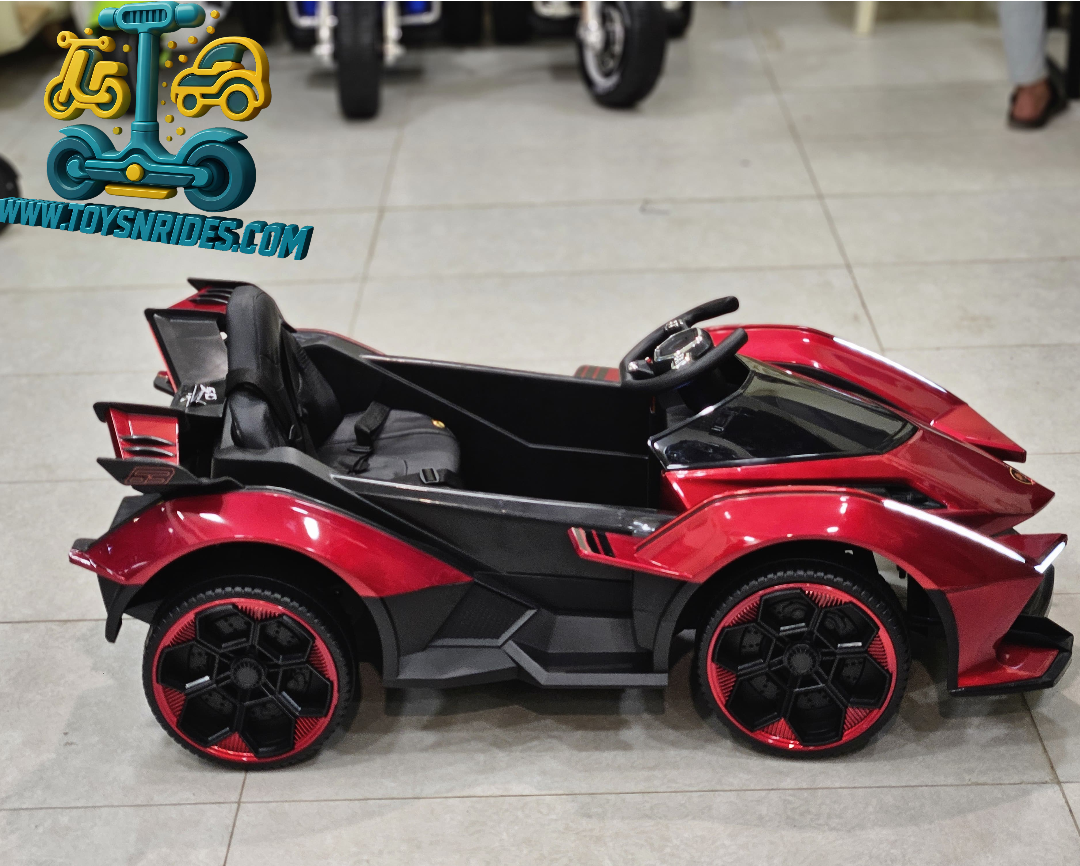 Red and black toy car on a tiled floor with 'www.toysnrides.com' logo.