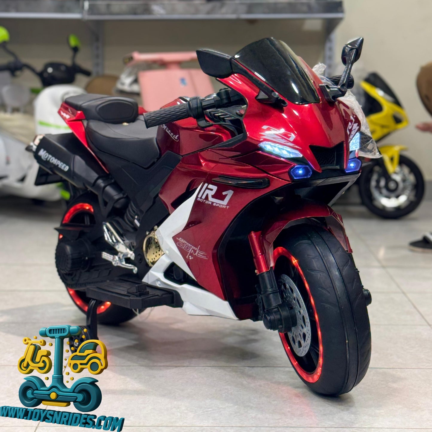 Red toy motorcycle with visible branding on a gray floor.