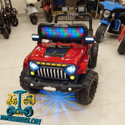 Red toy jeep with colorful lights on a tiled floor, brand 'TOYSNRIDES.COM' visible.