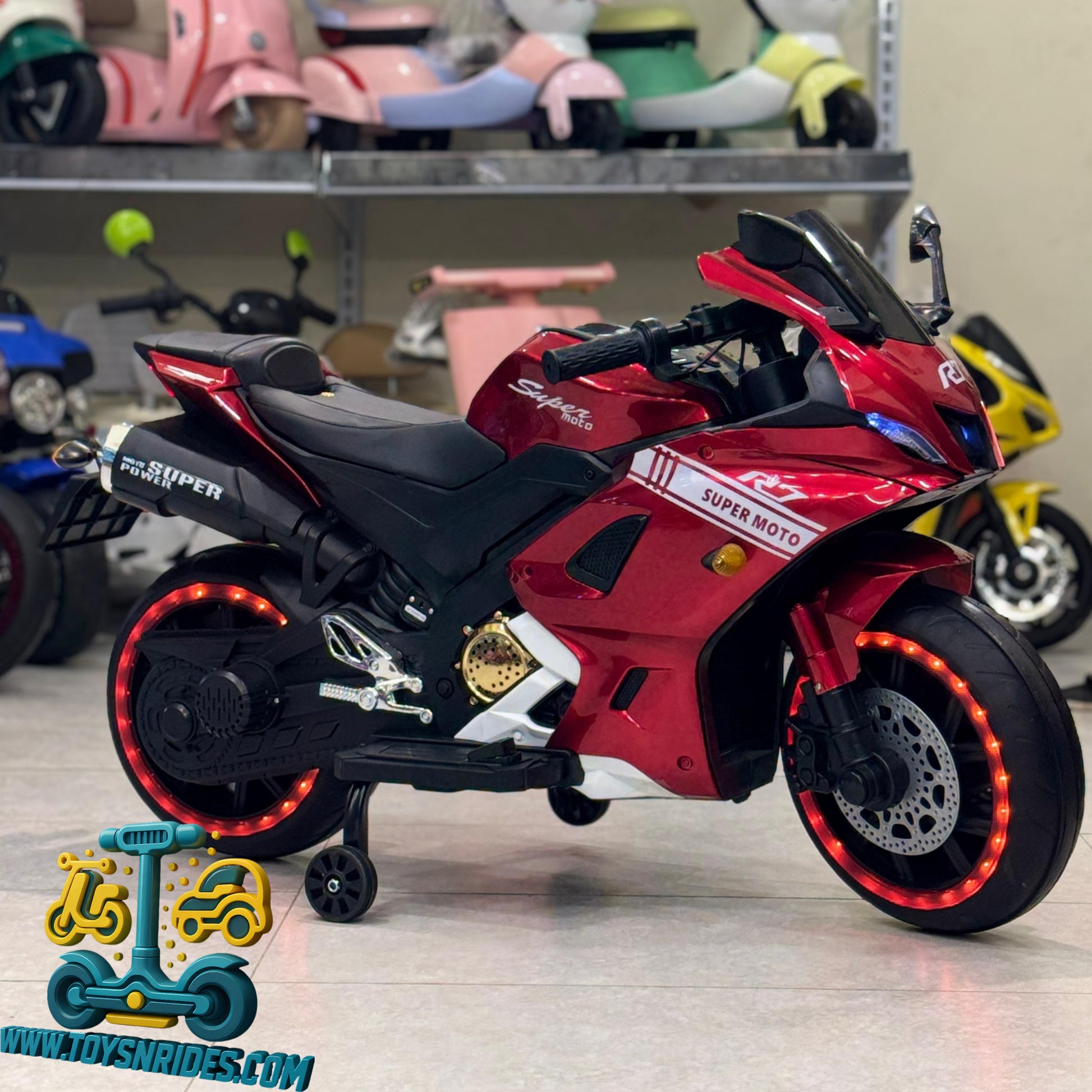 Red toy motorcycle with LED lights on a light gray surface, with other toys in the background.