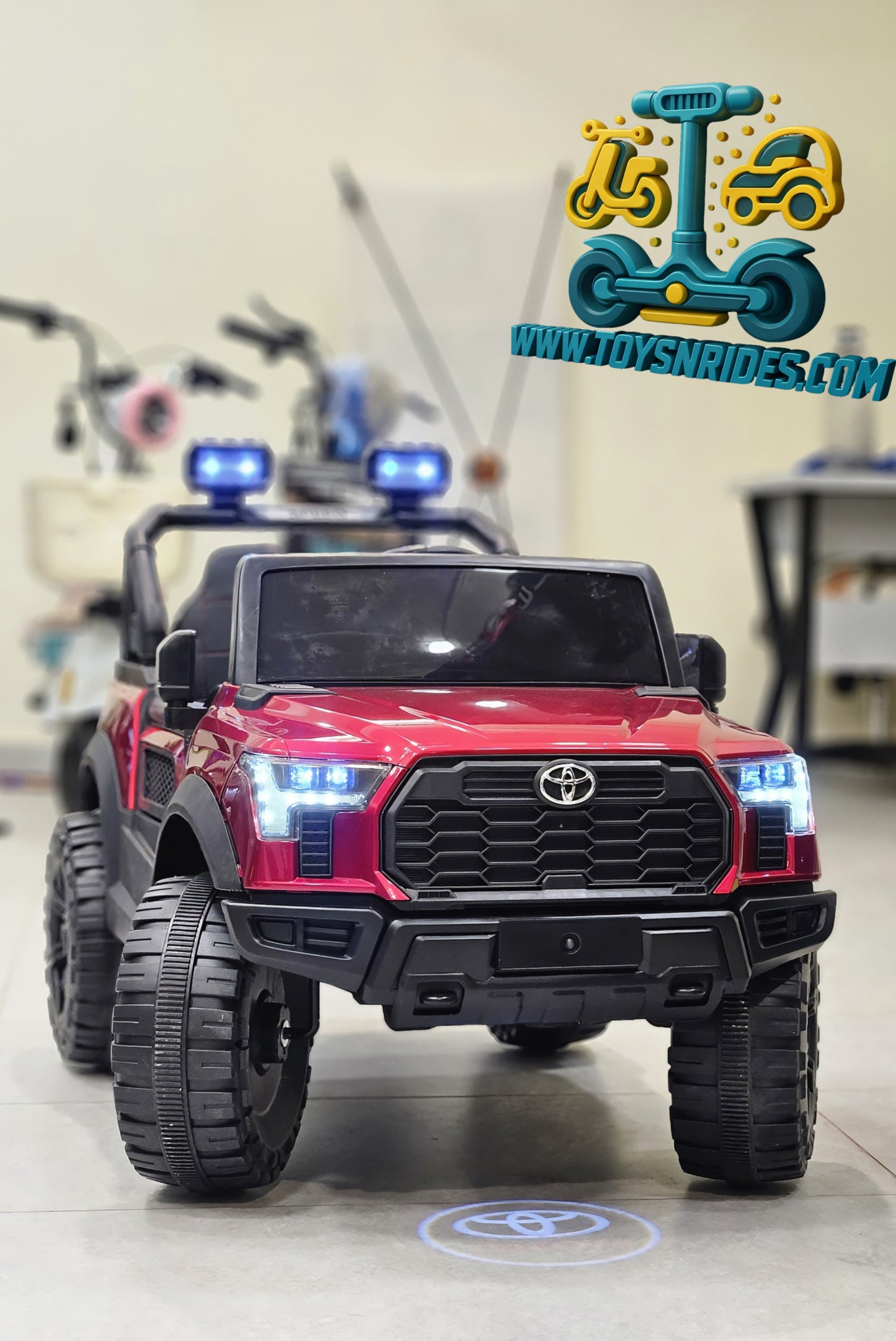 Red toy truck with lights on a tiled floor, brand 'Toys N Rides' visible.